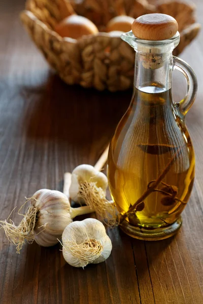 Head of garlic and olive oil bottle on a rustic table — Stock Photo, Image