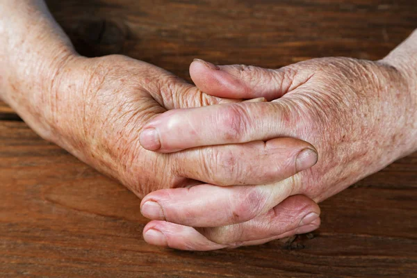 Mani di una donna anziana primo piano su un tavolo — Foto Stock