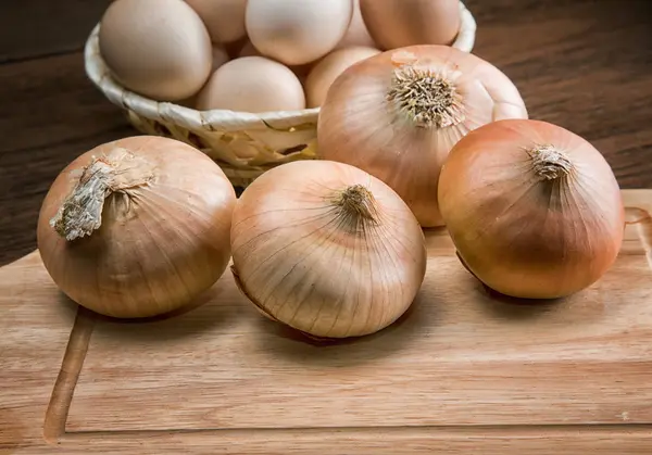 Stilleven met uien en kwarteleitjes op een keukentafel — Stockfoto