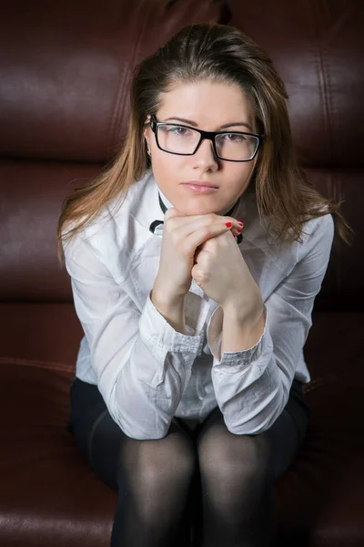 Girl in a shirt sits on the couch and looks thoughtfully into th — Stock Photo, Image