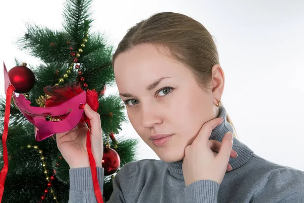 Ragazza con una maschera su uno sfondo di un albero di Natale — Foto Stock