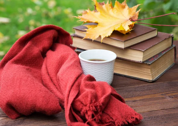 Tasse Tee auf dem Tisch mit einem Schal und einem Stapel Bücher — Stockfoto