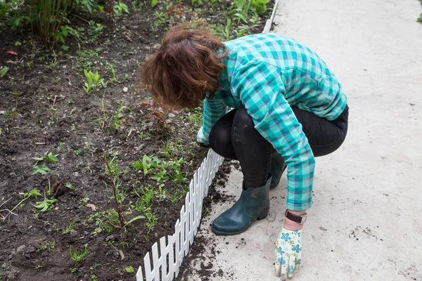 Kvinna fastställande ett dekorativa Staket på en blomma säng — Stockfoto