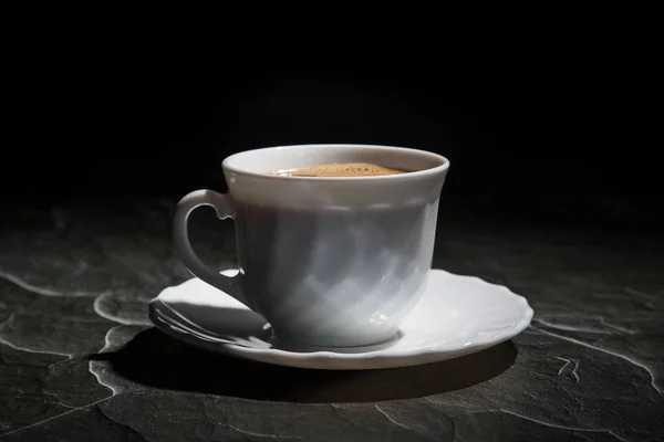 Taza de café blanco y un platillo sobre un fondo negro — Foto de Stock