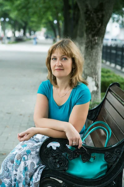 一个中年妇女坐在一个城市的长凳上的肖像 免版税图库图片