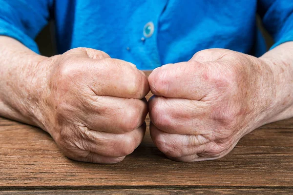 Handen van de close-up van een oude vrouw op een tafel — Stockfoto