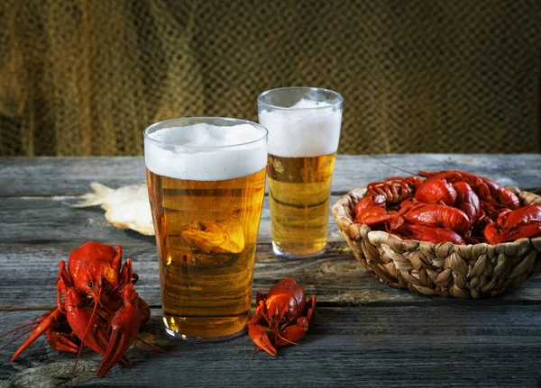 Smakelijke gekookte rivierkreeftjes en bier op oude tabel — Stockfoto