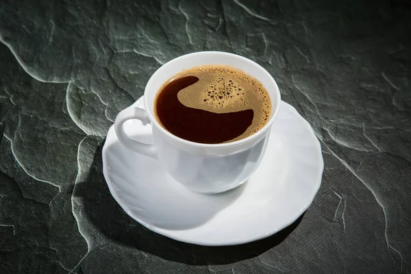 White cup of coffee and a saucer on a black background — Stock Photo, Image