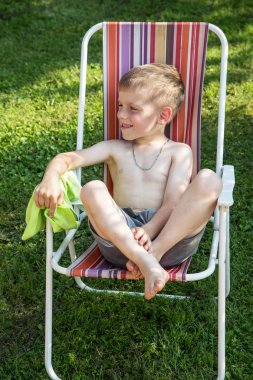 küçük çocuk bir plaj sandalyesini bahçede oturan