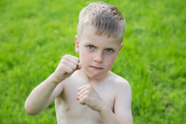 Pequeño niño boxeando en el césped en un día de verano — Foto de Stock