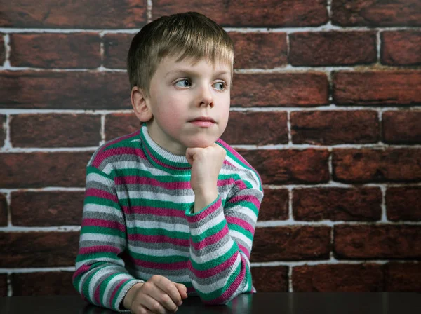 Niño de seis años con una expresión reflexiva en la pared backgr — Foto de Stock