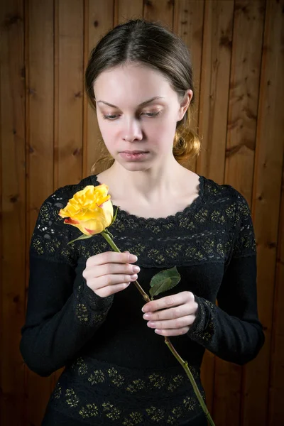 Menina em vestido preto com rosa amarela nas mãos — Fotografia de Stock