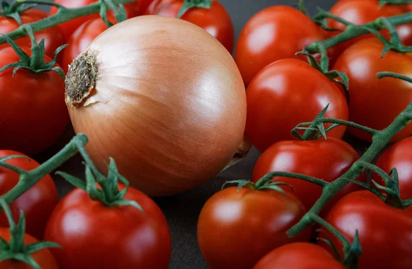 Gros oignon parmi les petites tomates sur la table — Photo