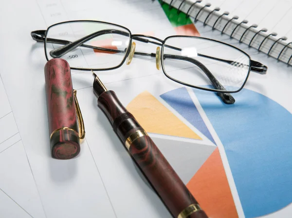 Gafas graduadas en las hojas con gráficos e información financiera —  Fotos de Stock