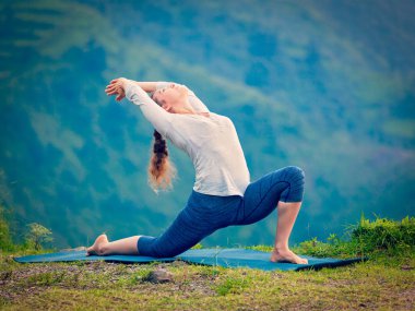 Sportif formda bir kadın dağlarda yoga yapıyor.