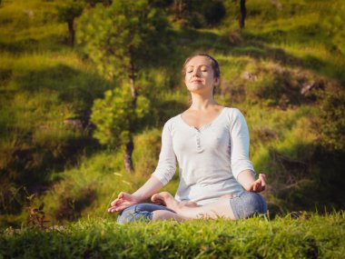 Genç, sportif, formda bir kadın dışarıda yoga yapıyor.