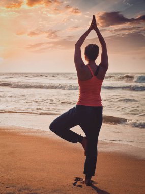 Sportif genç kadının yoga ağaç asana plajda yapması yerleştirmek