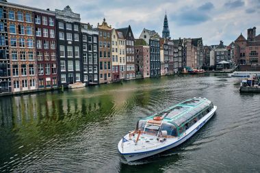 Kanal gezisi turist teknede Amsterdam'da Damrak kanal ve İskelesi