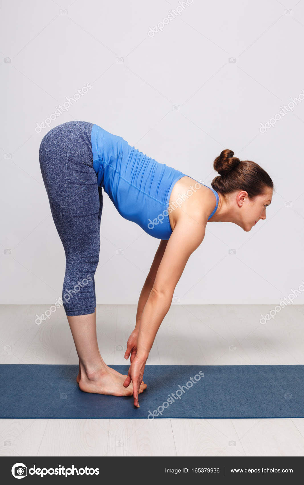 Woman doing yoga asana Uttanasana - standing forward bend Stock Photo by  ©DmitryRukhlenko 165379936