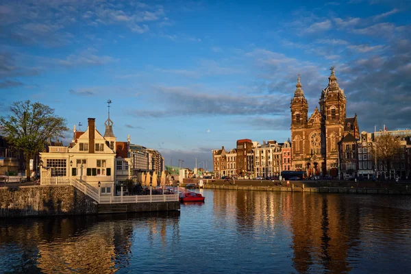 Amsterdamse gracht en de kerk van Sint Nicolaas op zonsondergang — Stockfoto