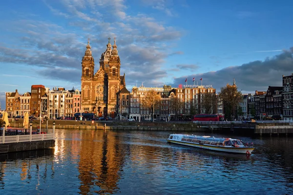 Toeristische boot in de Amsterdamse gracht en de kerk van Sint Nicolaas op — Stockfoto