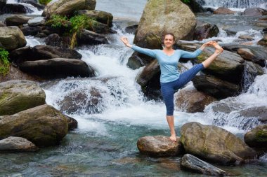 Şelalede Ashtanga Vinyasa Yoga yapan bir kadın.