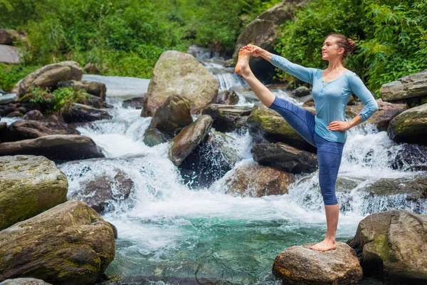 Женщина делает Ashtanga Vinyasa Yoga asana на открытом воздухе у водопада — стоковое фото