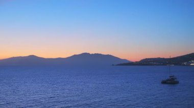 Yunanistan 'ın Mykonos kentinde günbatımı, limanda yolcu gemileri ve yatlarla