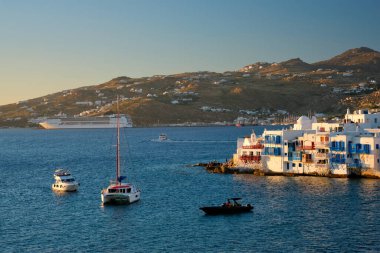 Yunanistan 'ın Mykonos kentinde günbatımı, limanda yolcu gemisi ve yatlarla