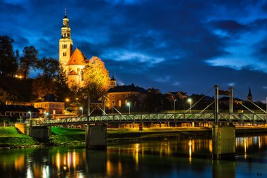 Leprosenhauskirche Kilisesi ve Mullner Steg Köprüsü gece aydınlandı. Salzburg, Avusturya