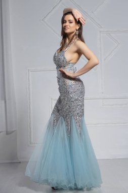 Güzel, genç bir esmer stüdyoda poz veriyor.