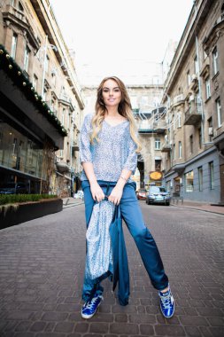 Açık havada poz veren genç bir sarışın.