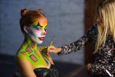 Makyaj sanatçıları güzel bir bayana su makyajı yapar.