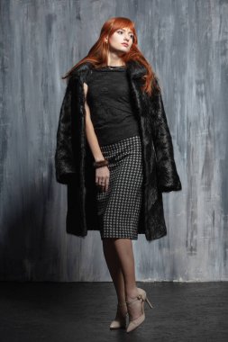 Çekici kızıl saçlı kadın stüdyoda poz veriyor.