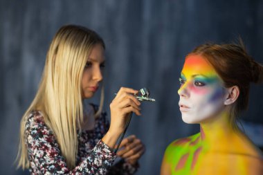 Ressam genç ve güzel bir modele yüz resmi çizer.