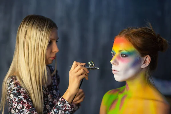 The artist puts a face painting on a beautiful young model — Stock Photo, Image