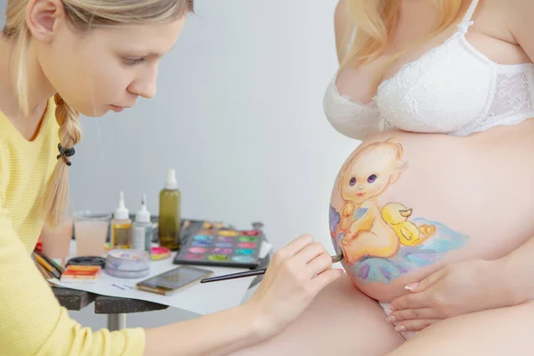 Pretty makeup artist draws a toddler on the belly — Stock Photo, Image