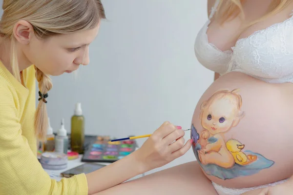 メイクアーティストは腹の上に幼児を描く — ストック写真
