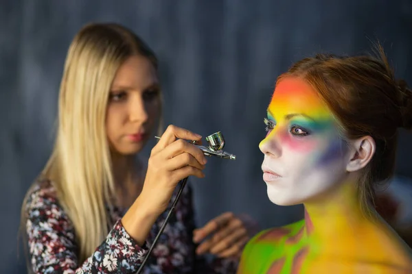 Artysta maluje twarz na młodej modelce — Zdjęcie stockowe