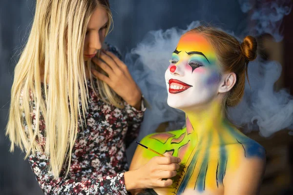 Gülümseyen bir kadına yüz resmi yapan sanatçı.