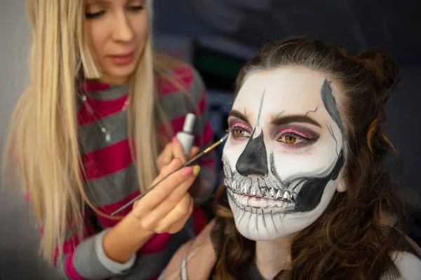 Make-up umělec dává tvář malování roztomilé ženy — Stock fotografie