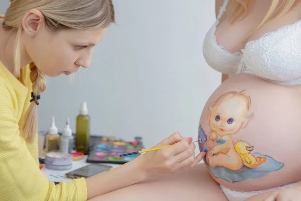 メイクアーティストは腹の上にかわいい赤ちゃんをペイント — ストック写真