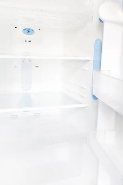 Interior of an empty open white refrigerator