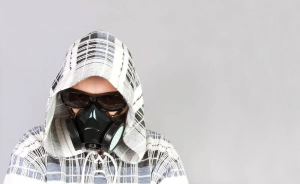 Coronavirus (COVID-19) and healthcare concept. Respiratory protection. Portrait of young man in black with respirator on his face over gray background