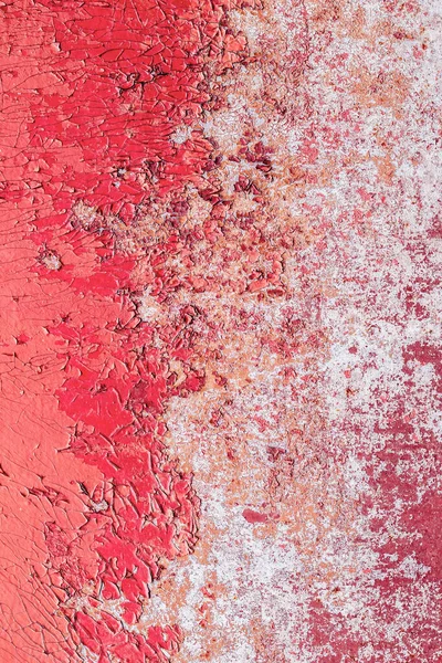 Old wall in color peeling red pink paint. Cracked exterior texture background