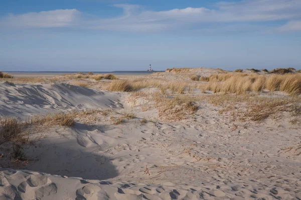 Paisaje con playa de arena y un faro en el fondo en — Foto de Stock