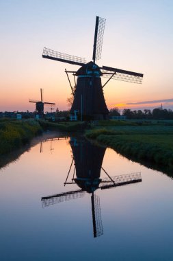 Sunrise with traditional Dutch windmills reflected in the calm w clipart
