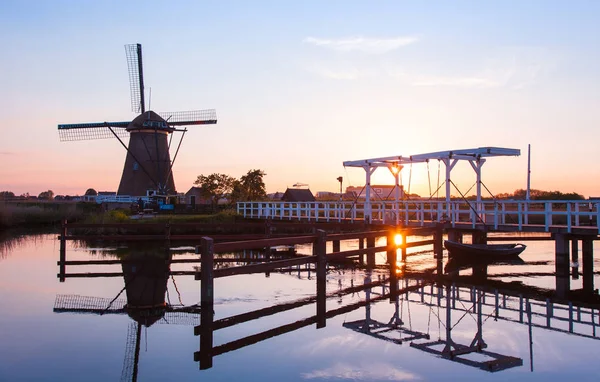 Puesta de sol con molinos de viento holandeses tradicionales y un puente de madera en K — Foto de Stock