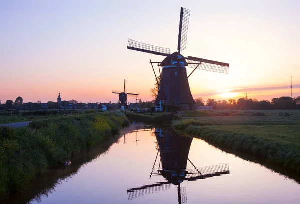 Puesta de sol con molinos de viento tradicionales holandeses reflejados en la calma wa —  Fotos de Stock