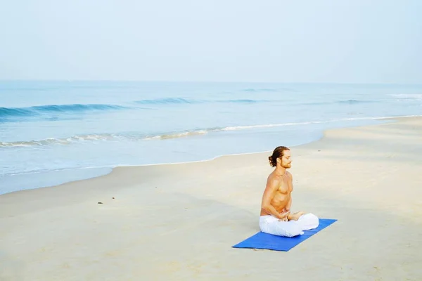 Mat 'in atletik adamı plajda yoga yapıyor. — Stok fotoğraf